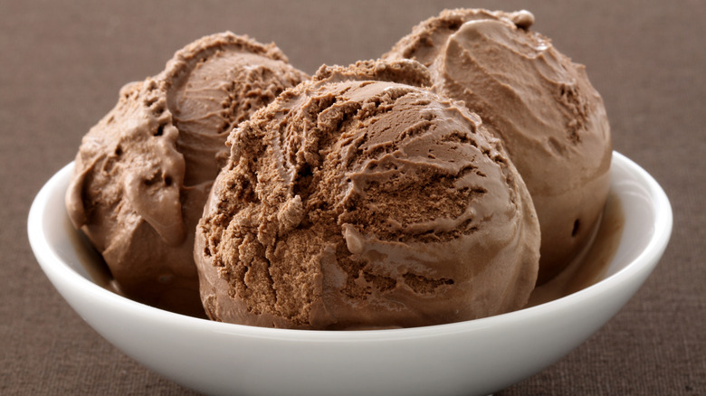 Closeup of three scoops of chocolate ice cream in a bowl.