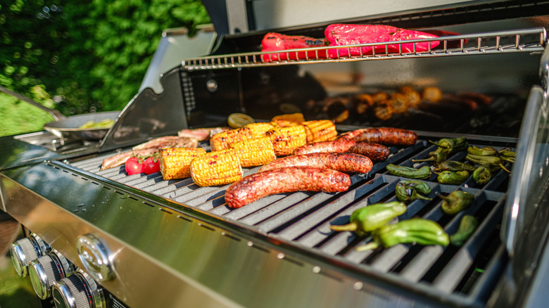 Corn sausage and vegetables on gas grill