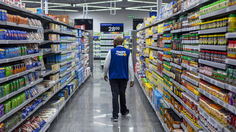 A Walmart employee walking through an aisle full of products