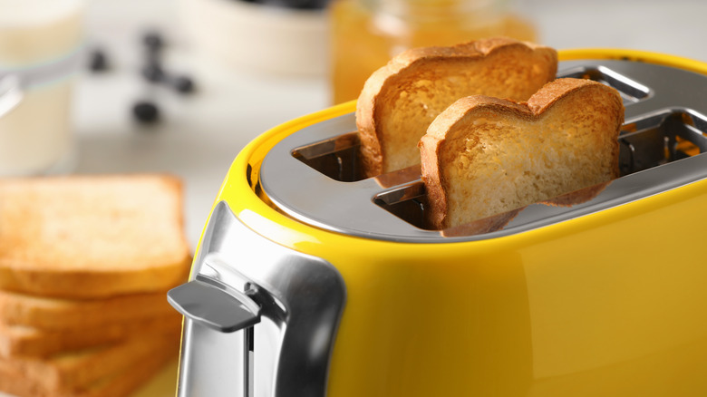 A yellow toaster with pieces of bread