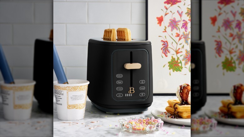The Beautiful by Drew Barrymore two-slice toaster with two popped waffles sticking out next to a tub of ice cream