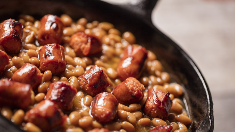 Closeup of hot dogs and baked beans in a cast iron skillet