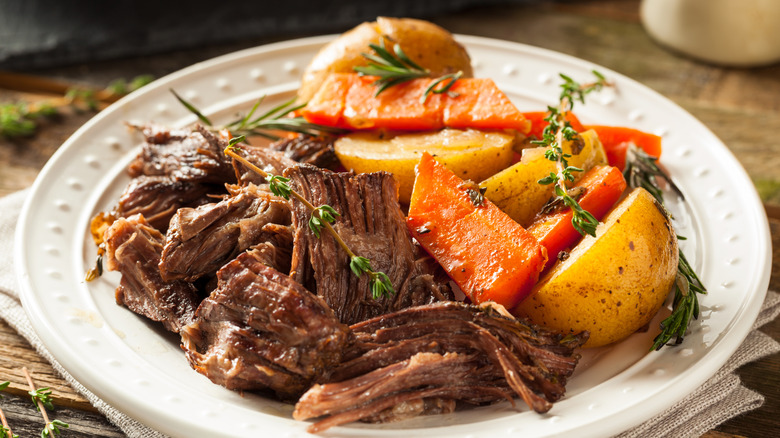 beef pot roast on white plate with carrots and potatoes
