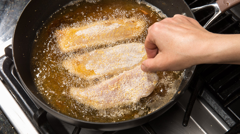 Home cook frying fish on the stove