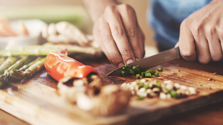 Closeup of person chopping vegetables on a cutting board