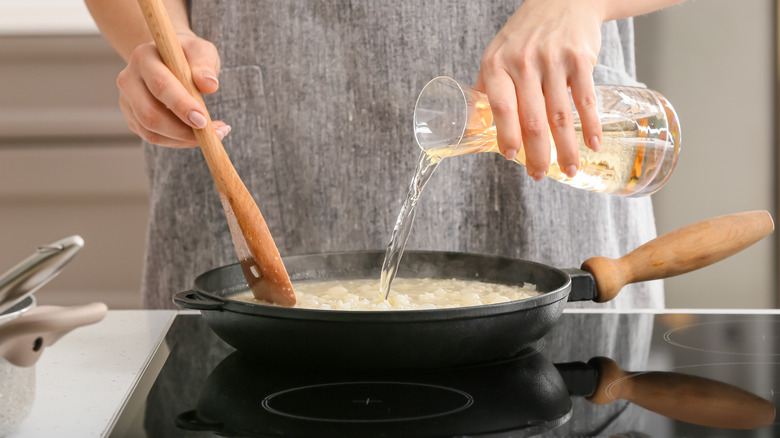Cooked white rice in silver pot with wooden spoon on top