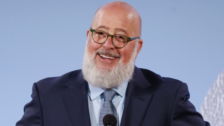 Andrew Zimmern smiling in suit with glasses