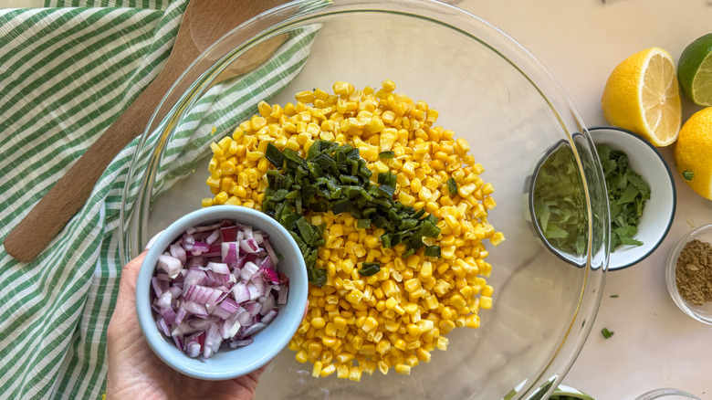 hand adding red onion to bowl