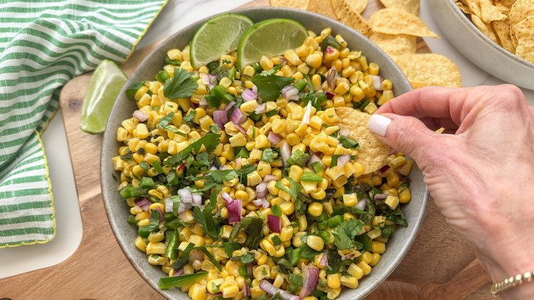 hand dipping chip into salsa