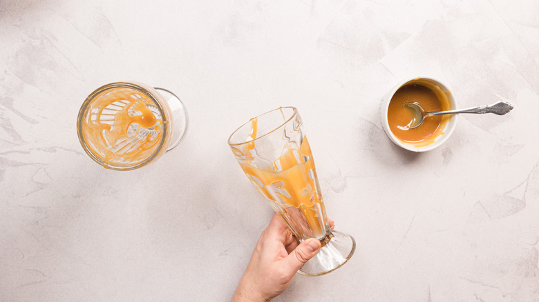 Hand holding a glass with caramel drizzle inside