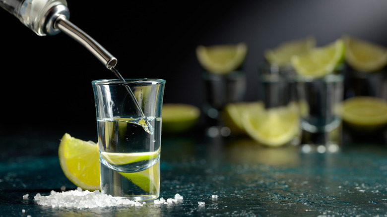 Pouring tequila shots with lime wedges