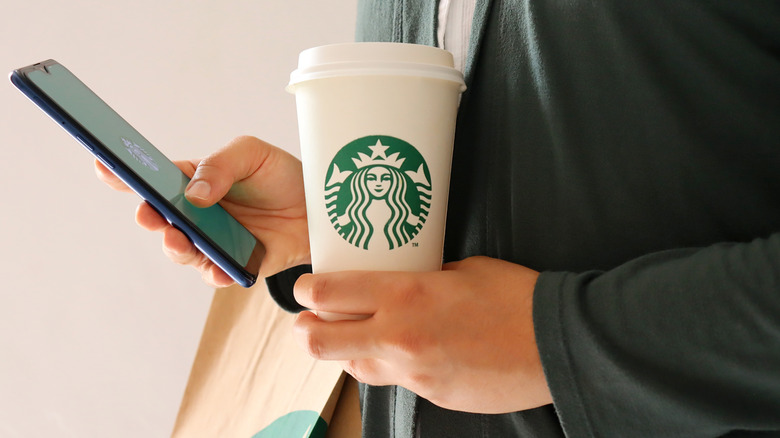 Student holding Starbucks cup, cell phone