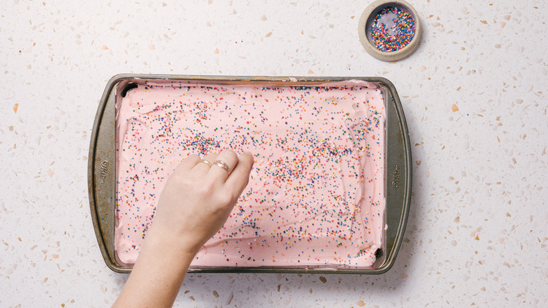 Adding sprinkles to pink cake