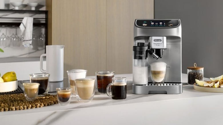 A De'Longhi automatic espresso machine on a counter next to a variety of espresso-based drinks