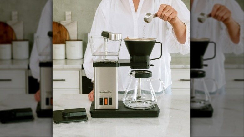 A person scooping ground coffee into the filter of the SimplyGood Plastic Free Blooming Coffee Maker