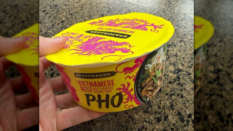Hand holding Snapdragon Vietnamese beef pho in yellow packaging
