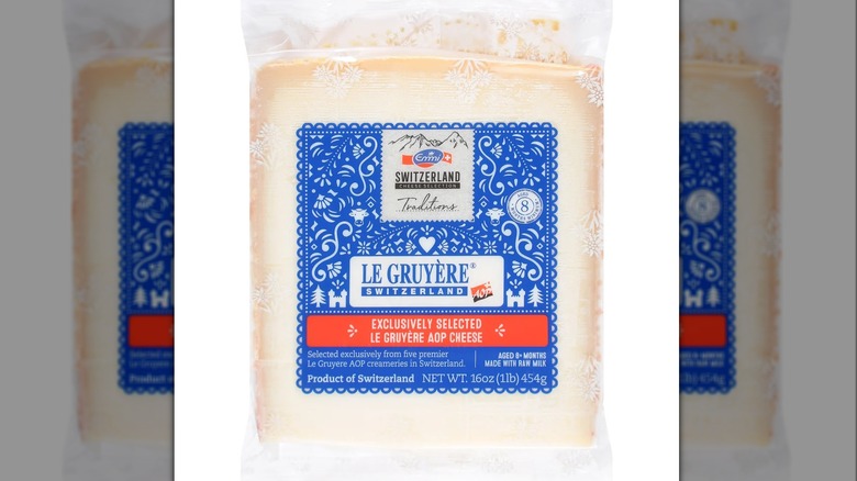 Wedge of gruyere cheese it it's packaging against a white background.