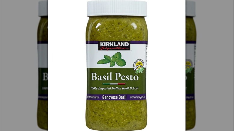 A jar of Kirkland Signature Imported Basil Pesto against a white background.