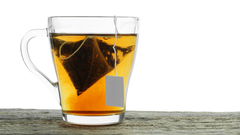 Tea bag in a glass cup with a hot drink on a white background