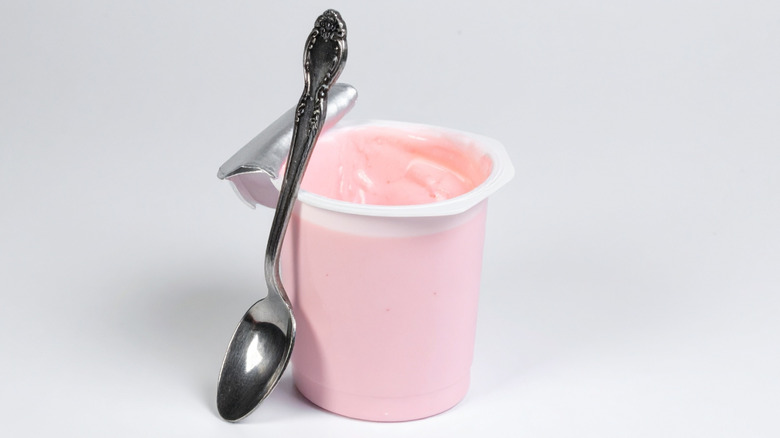Strawberry-flavored yogurt in an open plastic cup with a metal spoon
