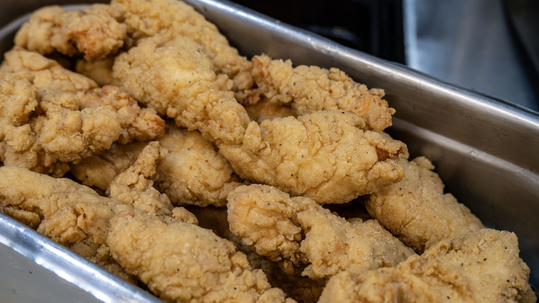 A metal prep pan containing breaded, fried chicken tenders