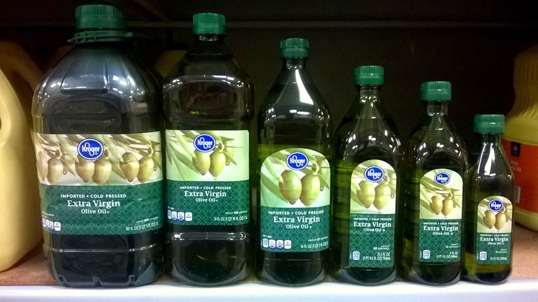 Bottles of Kroger brand extra virgin olive oil arranged from largest to smallest from left to right on store shelf