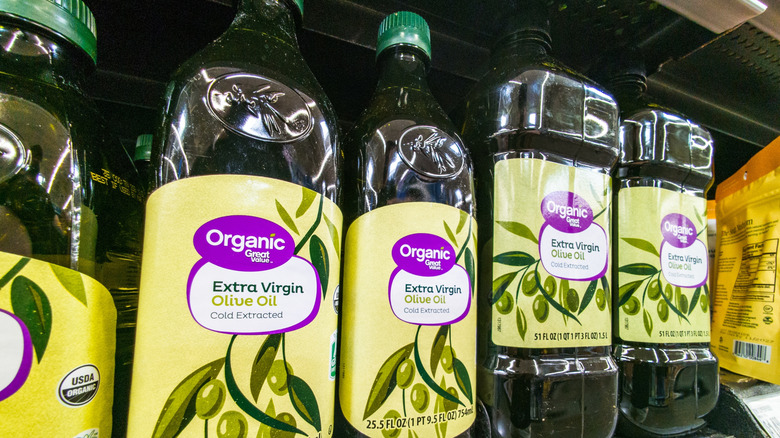 Green bottles of Walmart brand Great Value organic extra virgin olive oil on store shelf
