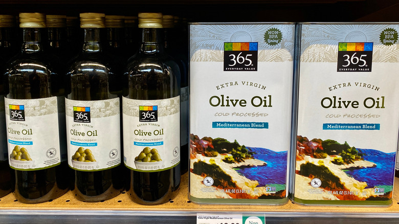 Boxes and bottles of Whole Foods 365 extra virgin olive oil on store shelf