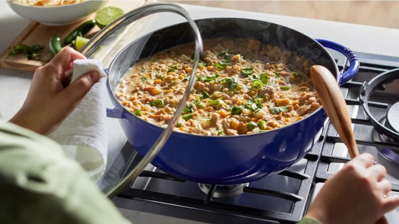 A person cooking in a Staub Le Grande 7.4-Quart Cast Iron Dutch Oven