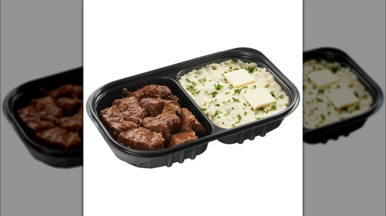 Black tray of Kirkland Signature Braised Beef with Yukon Mashed Potatoes prepared meal on white background