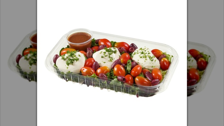 Kirkland Signature Burrata Salad prepared meal with cheese, tomatoes, greens, and cup of dressing in plastic tray