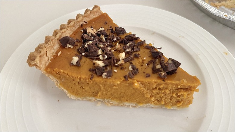 Pumpkin pie with pieces of nuts and chocolate on top
