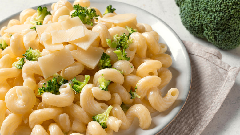 A white plate of homemade mac and cheese topped with broccoli and parmesan cheese