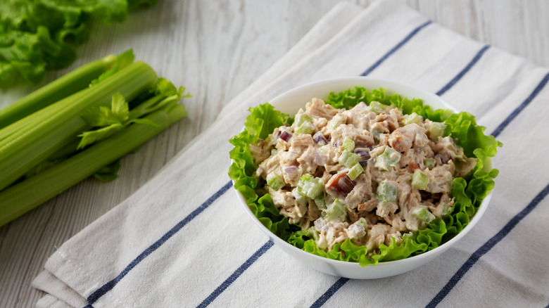 A white bowl of homemade chicken salad with celery, onions, dried cranberries, and pecans