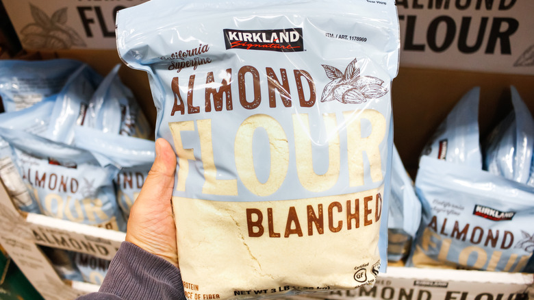 Costco Kirkland Signature almond flour in a bag, being held by hand in front of store supply