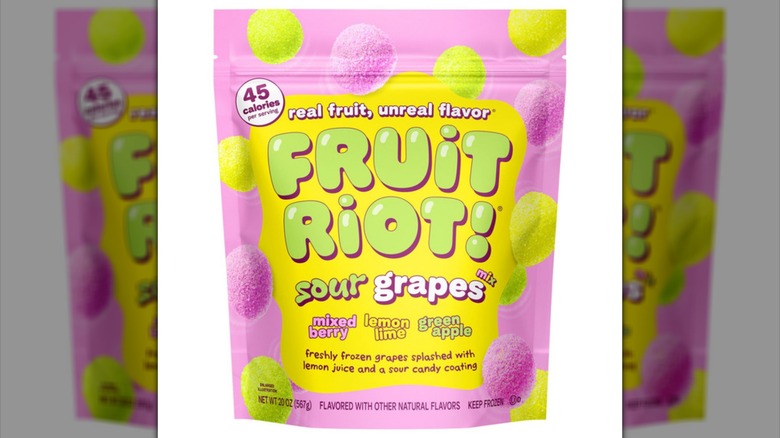 Pink and yellow bag of Fruit Riot Sour Mixed Grapes frozen fruit snack on white background