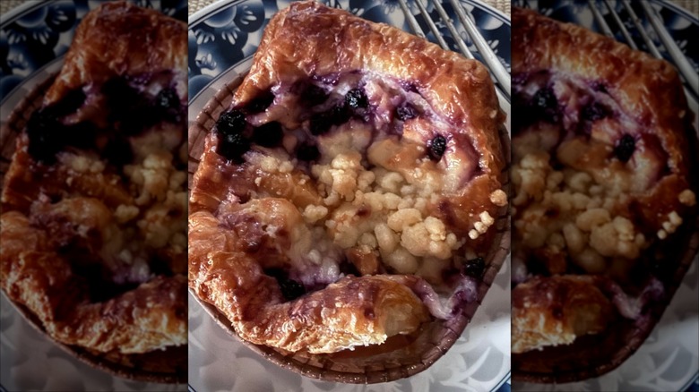 A close-up of a Kirkland Signature Blueberry Caramelized Cheesecake Croissant on a blue and white plate