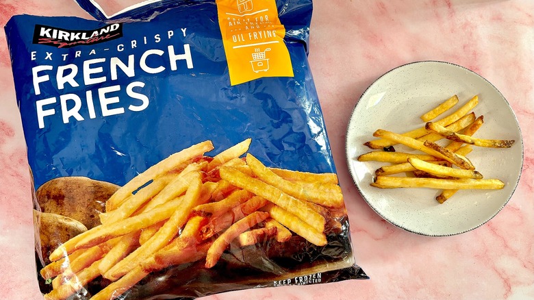 Kirkland Signature Extra Crispy French Fries on white plate next to bag, on pink marble surface