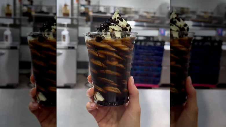 A woman's hand holding up a Cookie Crunch Sundae from the Costco food court