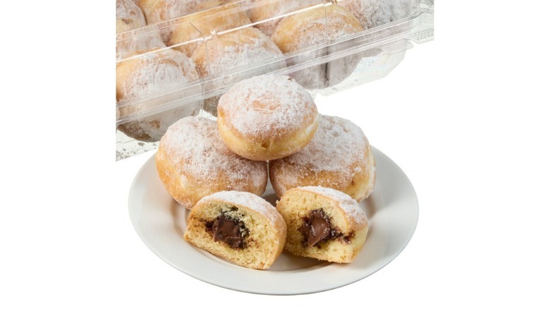 Costco bakery Mini Beignets Filled with Chocolate Hazelnut in a plastic bakery container and on a white plate with one cut in half to show filling