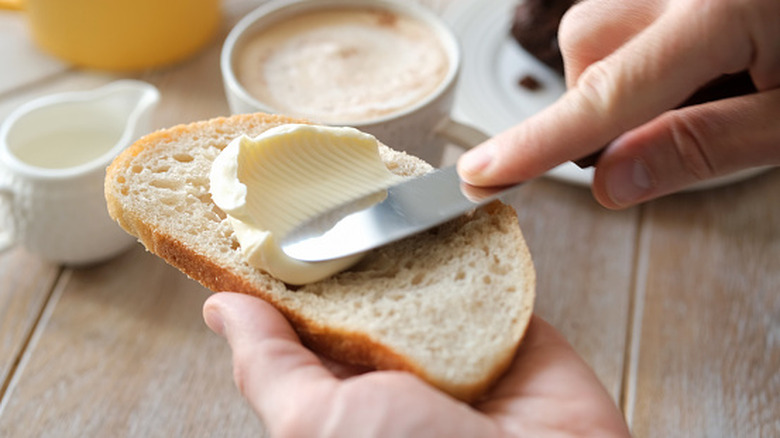 person putting butter on toast