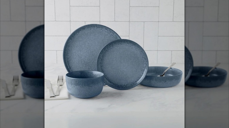 Blue bowls and plates from Denmark 16-piece Dinnerware Set displayed on gray surface with silver forks