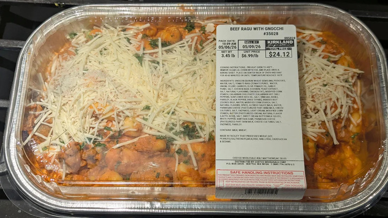 Ready-made meal topped with lots of cheese in an aluminum tray with plastic lid.