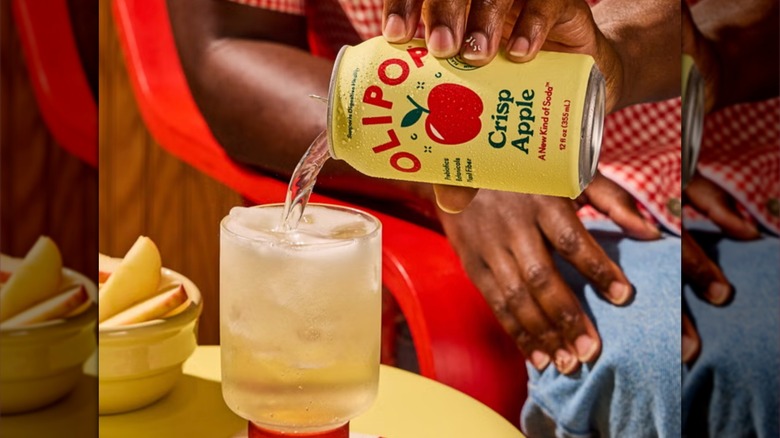 Olipop Crisp Apple drink poured into a glass with apple slices on table