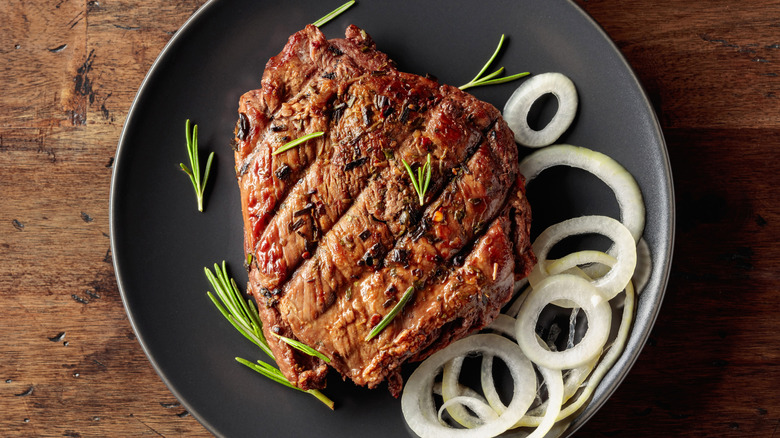 Grilled ribeye beef steak with rosemary and marinated onion
