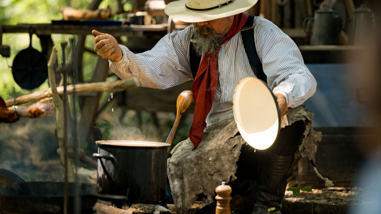 Cowboy cooking something over a campfire