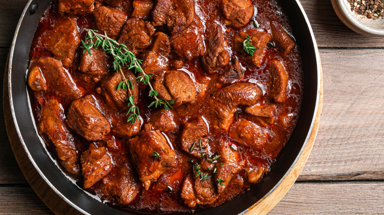 Rustic stew with beef in pan on wooden table