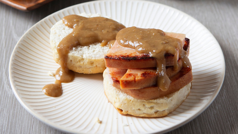 Lumpy brown gravy over ham and biscuits