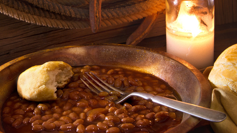 A metal plate of beans, with cowboy biscuits.