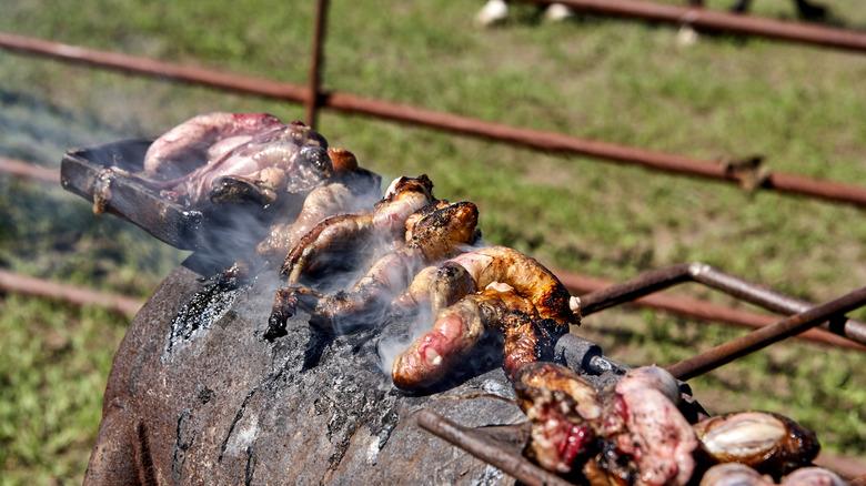Calf testicles cooking outside on a charcoal grill
